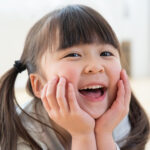頬に手を添えこちらを見て笑う子供